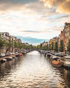 An Amsterdam canal at dusk, boats moored along the quay